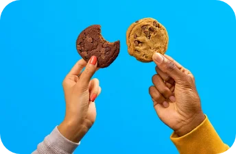 Chocolate chip cookies held against a blue background.